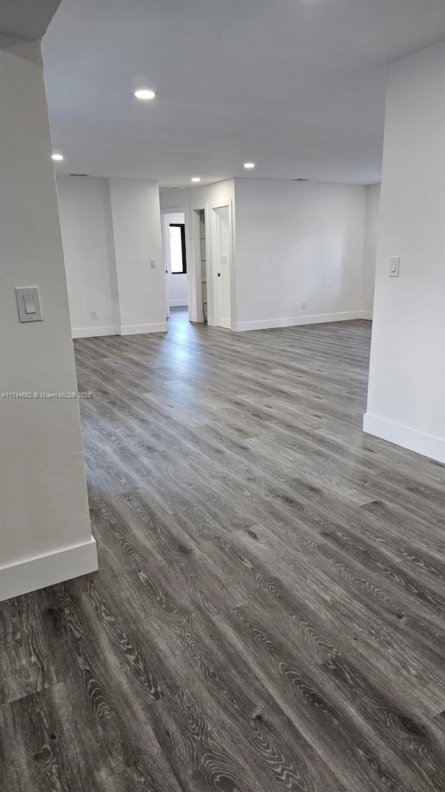 empty room with dark wood-type flooring, recessed lighting, and baseboards