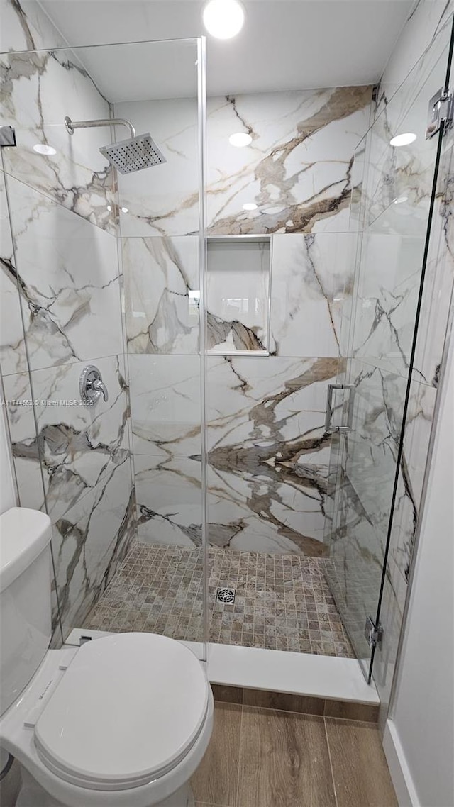 bathroom with a marble finish shower and toilet