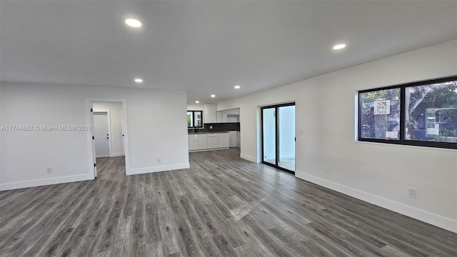 unfurnished living room featuring dark wood-style floors, a wealth of natural light, baseboards, and recessed lighting