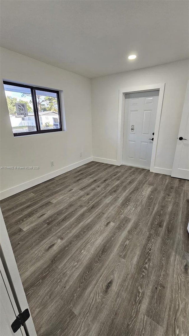 spare room with dark wood-style floors, recessed lighting, and baseboards