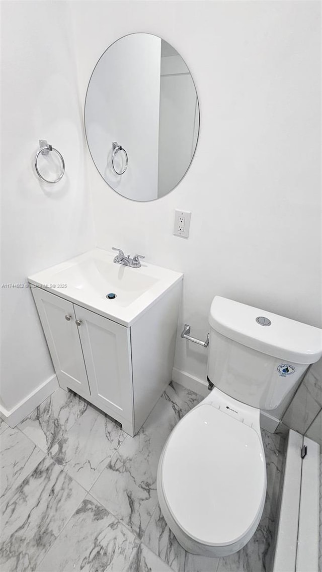 bathroom with toilet, marble finish floor, baseboards, and vanity