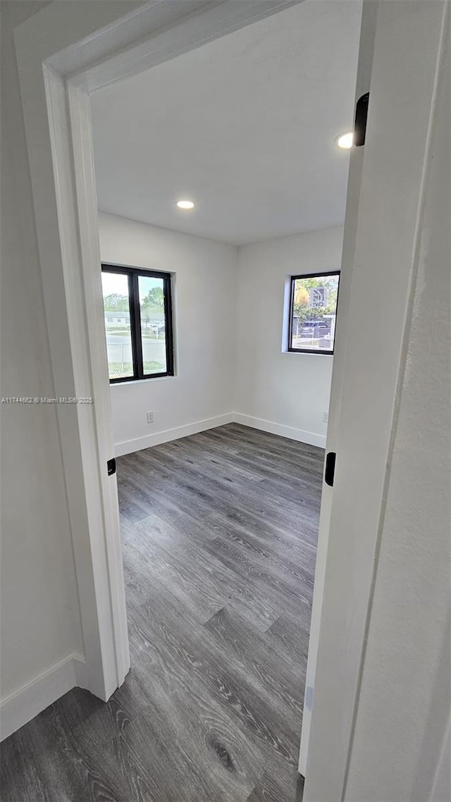 spare room featuring a wealth of natural light, dark wood-style flooring, and baseboards