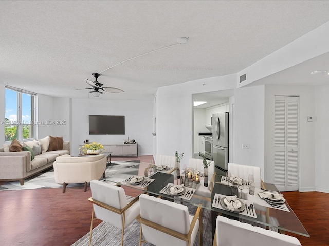 living room featuring ceiling fan, a textured ceiling, baseboards, and wood finished floors