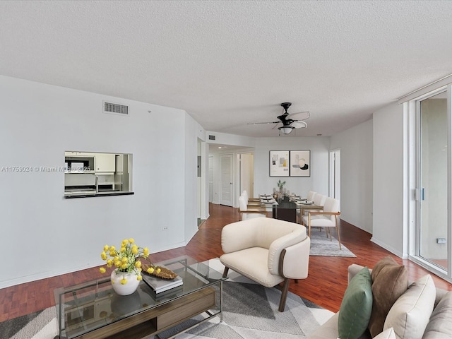 living room with visible vents, a textured ceiling, and wood finished floors