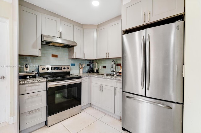 kitchen with light tile patterned floors, stainless steel appliances, decorative backsplash, a sink, and under cabinet range hood