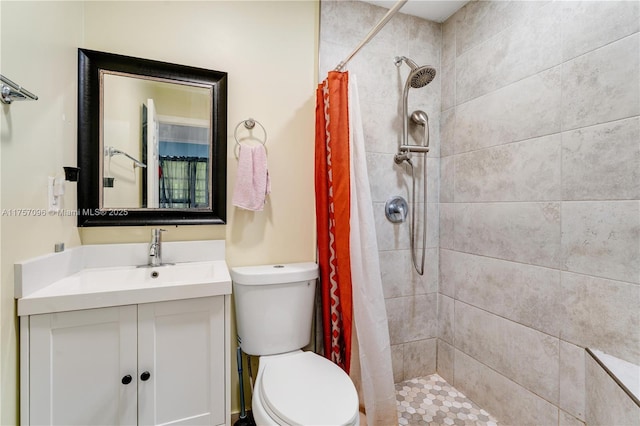 full bath with vanity, a tile shower, and toilet