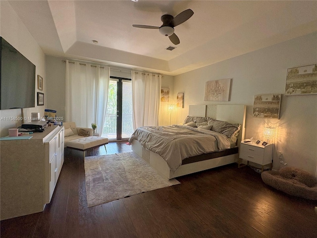 bedroom featuring visible vents, access to outside, wood finished floors, a raised ceiling, and ceiling fan