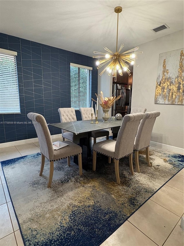 tiled dining room with visible vents, a notable chandelier, and tile walls