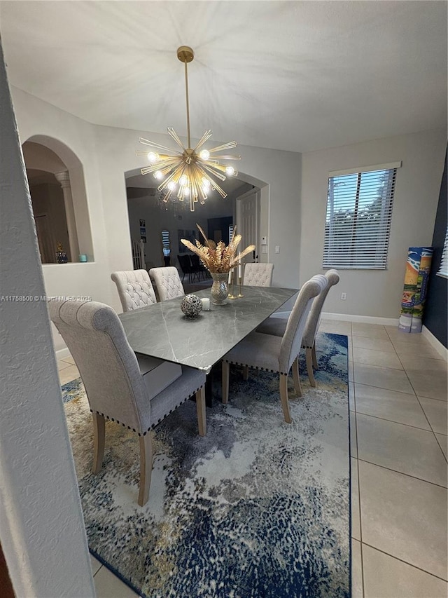 dining space with a notable chandelier, arched walkways, baseboards, and light tile patterned floors