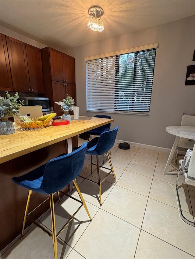 dining space featuring light tile patterned floors, a textured ceiling, and baseboards