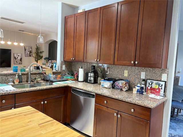 kitchen featuring tasteful backsplash, dishwasher, light stone counters, arched walkways, and a sink