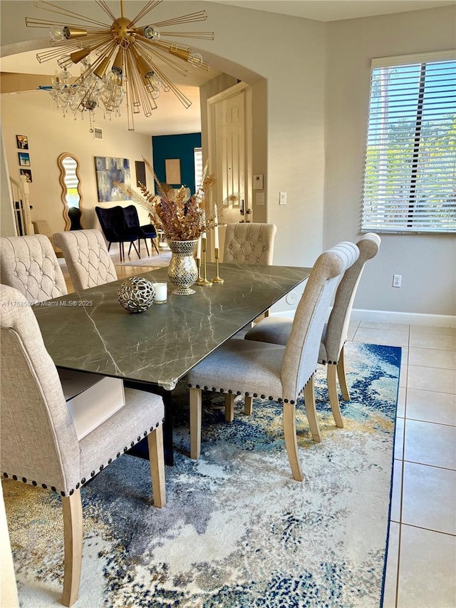 dining space with tile patterned flooring, arched walkways, and baseboards