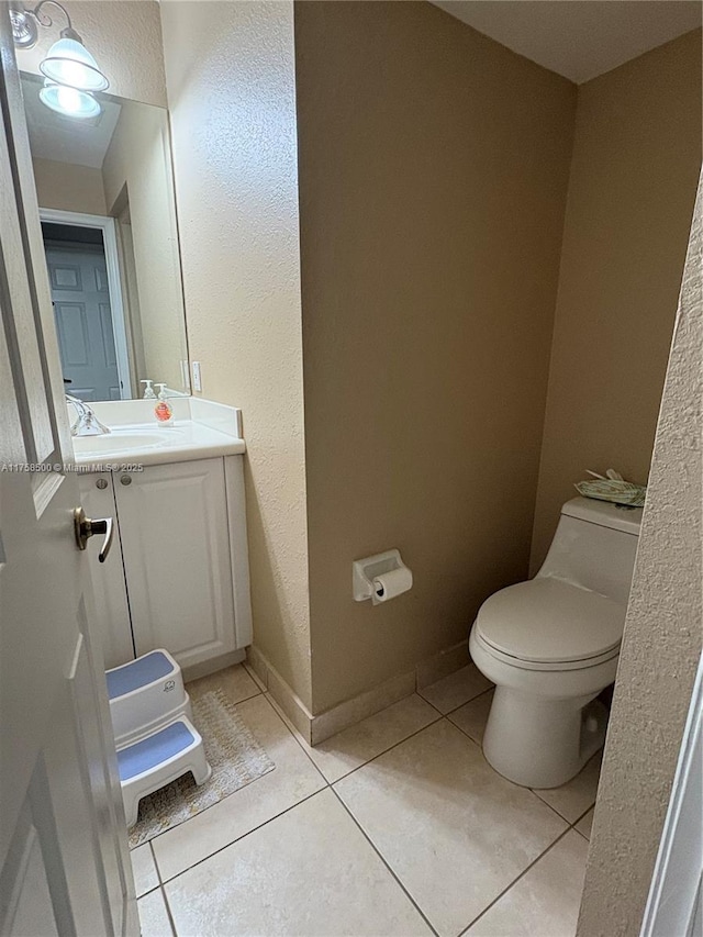 bathroom featuring tile patterned flooring, toilet, vanity, and baseboards