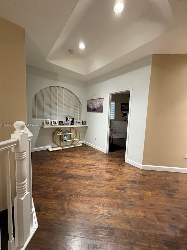 spare room featuring recessed lighting, baseboards, a raised ceiling, and wood finished floors