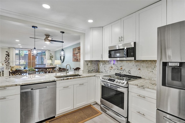 kitchen with stainless steel appliances, a sink, white cabinetry, decorative backsplash, and crown molding