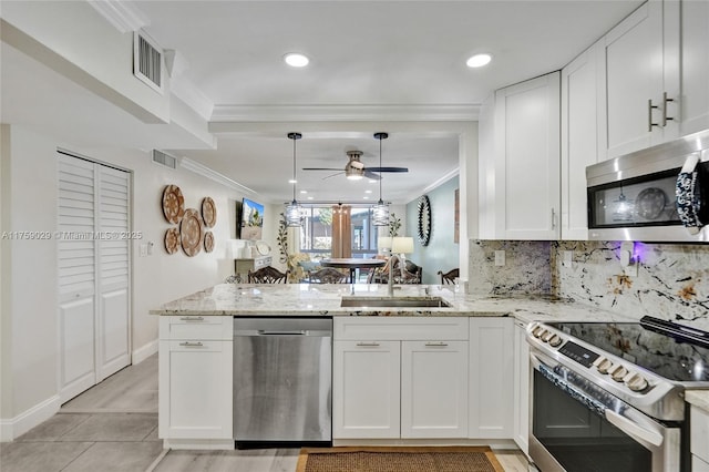 kitchen with appliances with stainless steel finishes, crown molding, a sink, and a peninsula