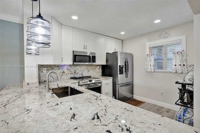 kitchen with decorative backsplash, light stone counters, stainless steel appliances, white cabinetry, and a sink