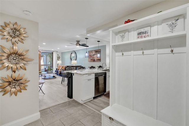 kitchen with white cabinets, dishwashing machine, light stone counters, open floor plan, and light tile patterned flooring