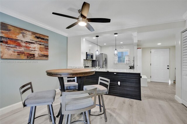 dining space featuring baseboards, ornamental molding, recessed lighting, and light wood-style floors