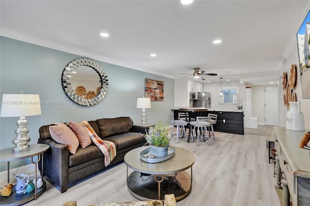 living area featuring baseboards, ceiling fan, crown molding, light wood-style floors, and recessed lighting