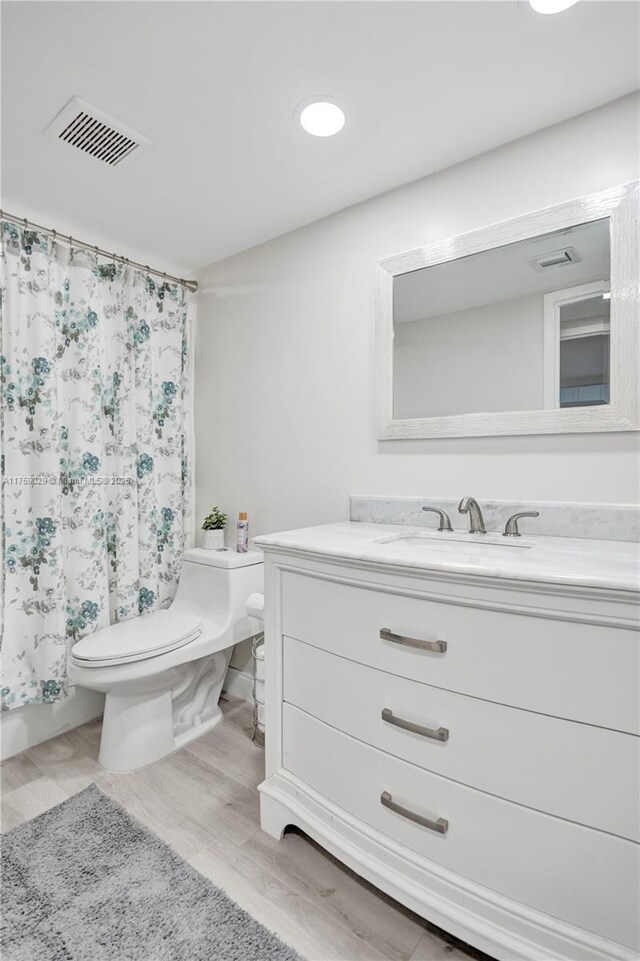 full bath with visible vents, toilet, wood finished floors, shower / tub combo with curtain, and vanity