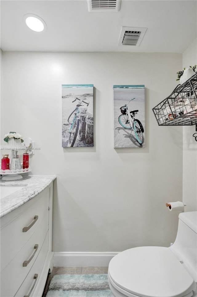 half bathroom featuring baseboards, visible vents, vanity, and toilet