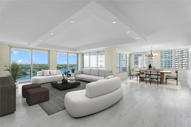 living area with recessed lighting, an inviting chandelier, a healthy amount of sunlight, and light wood finished floors