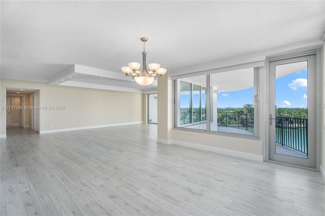 interior space featuring baseboards, light wood-style floors, an inviting chandelier, and a textured ceiling