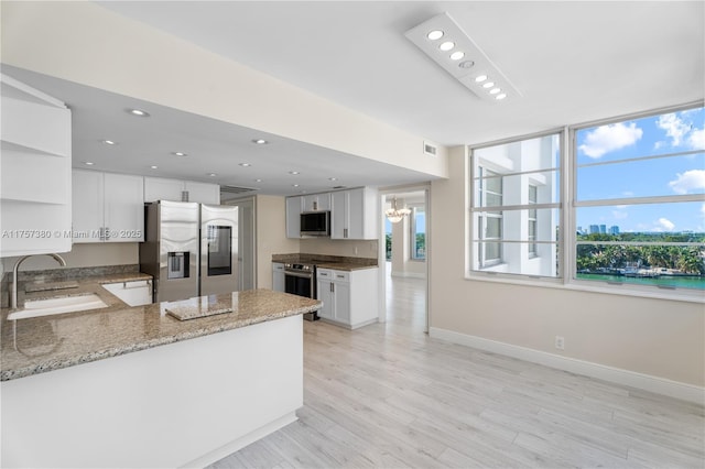 kitchen featuring open shelves, light wood-style flooring, appliances with stainless steel finishes, a sink, and a peninsula