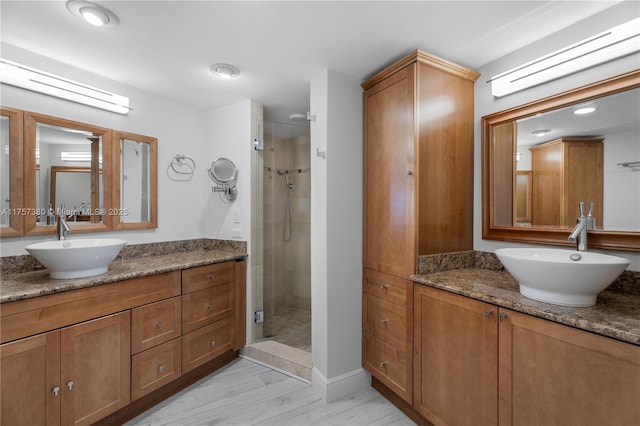 bathroom featuring a shower stall, wood finished floors, and vanity