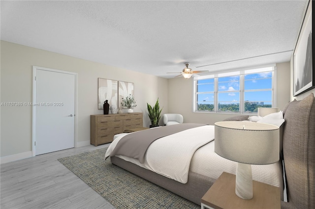 bedroom featuring a ceiling fan, baseboards, light wood finished floors, and a textured ceiling