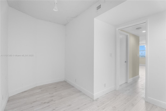 unfurnished room with light wood-type flooring, visible vents, and baseboards