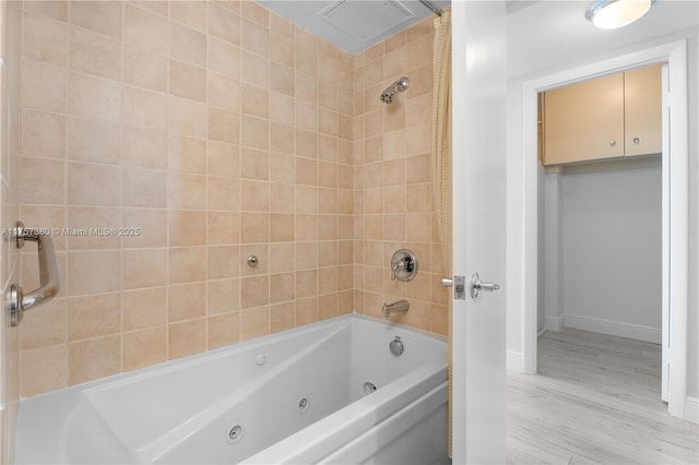 full bath with a combined bath / shower with jetted tub, baseboards, and wood finished floors