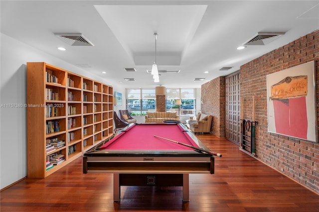 rec room featuring wood-type flooring, visible vents, and brick wall