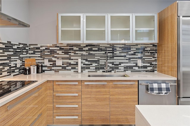 kitchen with light countertops, backsplash, appliances with stainless steel finishes, a sink, and ventilation hood