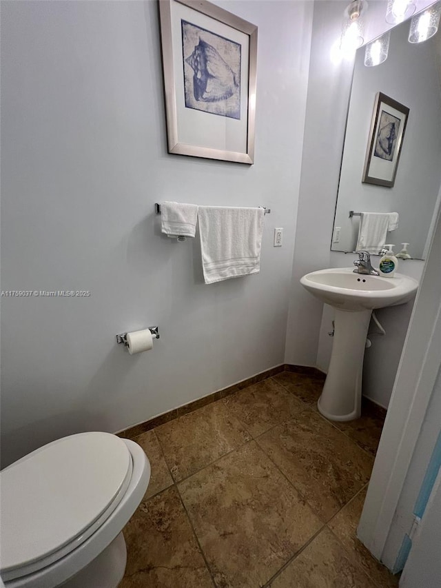 bathroom featuring toilet, baseboards, and a sink