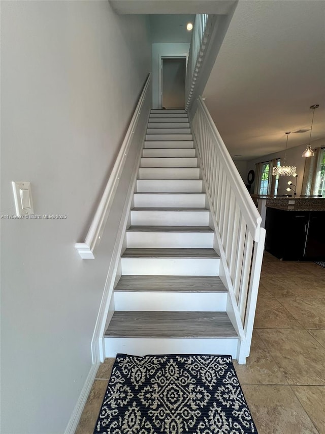 stairway featuring an inviting chandelier