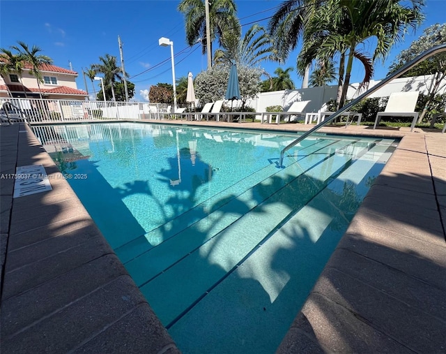 pool with a patio area and fence