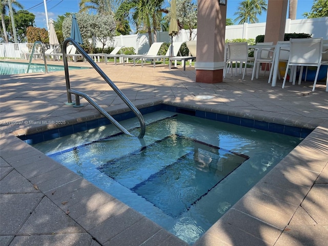 pool featuring a hot tub, fence, and a patio