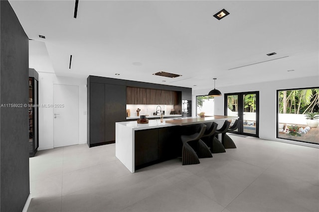 kitchen with a spacious island, modern cabinets, decorative light fixtures, light countertops, and french doors