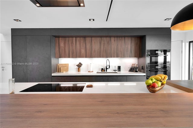 kitchen with light countertops, a sink, black appliances, and modern cabinets