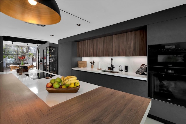 kitchen featuring black appliances, modern cabinets, a sink, and light countertops