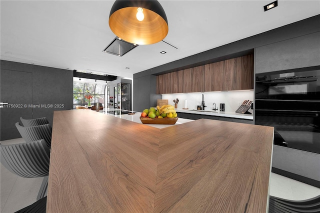 kitchen with dobule oven black, tile patterned flooring, modern cabinets, and light countertops