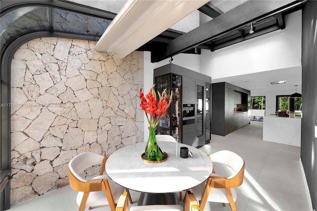 tiled dining area featuring beam ceiling