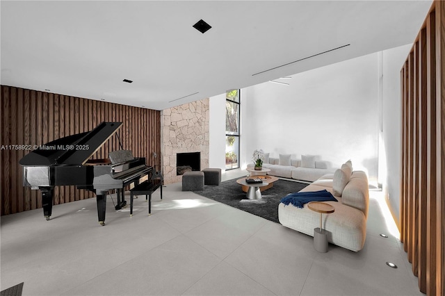 living area with a stone fireplace, wood walls, a wall of windows, and visible vents