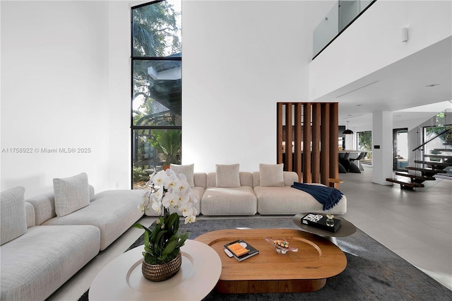 living room featuring expansive windows, a high ceiling, and stairs