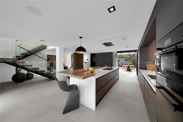 kitchen with a wall of windows, hanging light fixtures, an island with sink, and modern cabinets