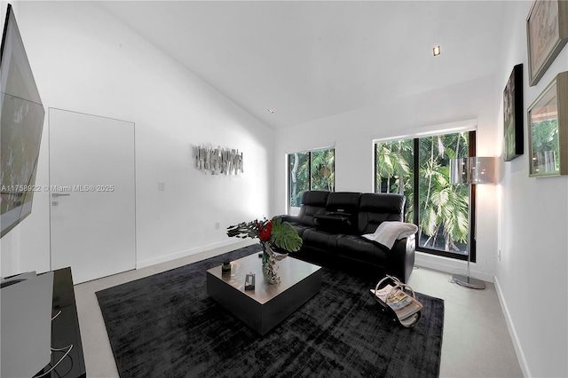 living room featuring high vaulted ceiling and baseboards