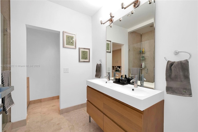 full bathroom featuring double vanity, baseboards, a sink, and tiled shower