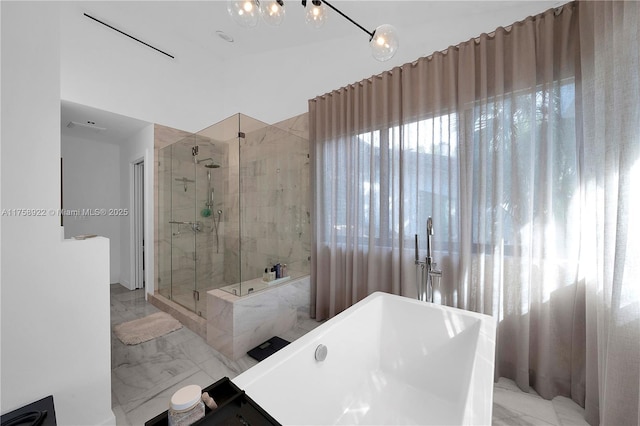 bathroom featuring marble finish floor, a soaking tub, and a shower stall